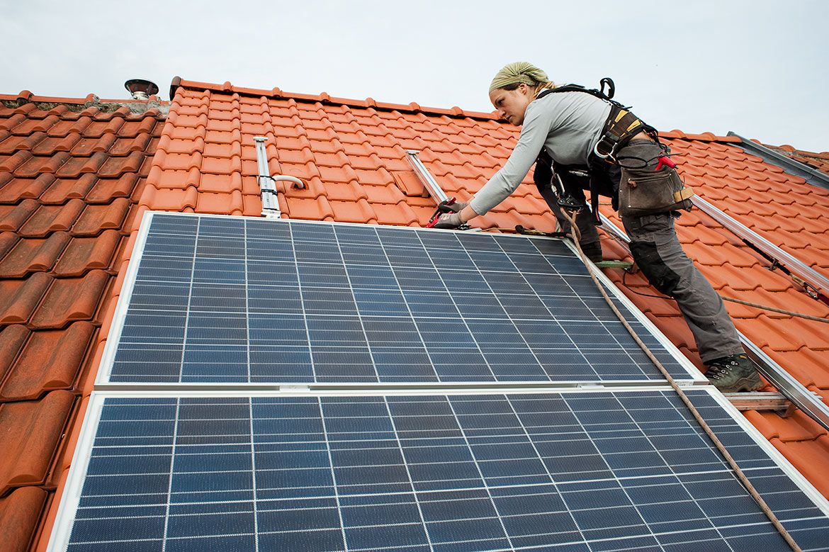 Een vrouw plaatst zonnepanelen op een dak.
