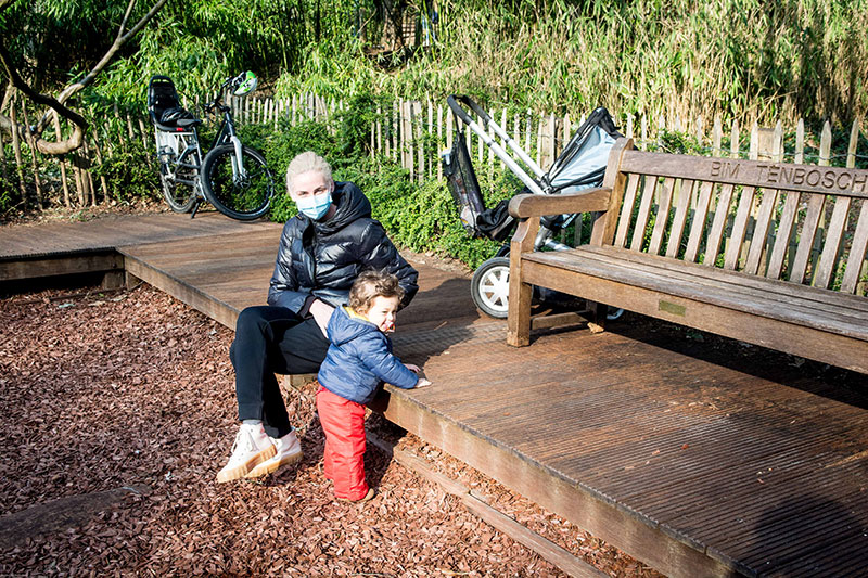 Een vrouw met mondmasker en haar kindje in de speeltuin van het Tenboschpark.