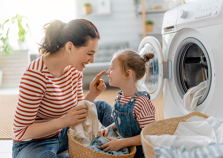 Een vrouw en een klein meisje voor een wasmachine.