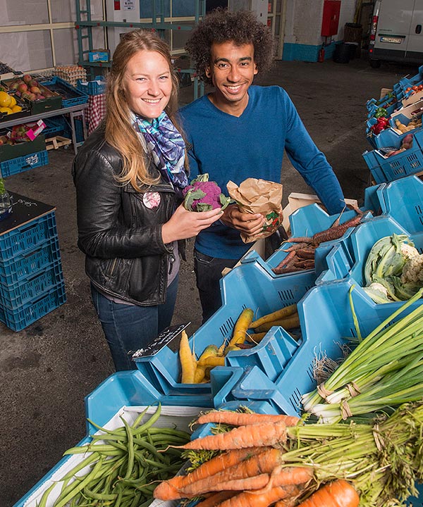 Een vrouw en een man kopen lokale groenten.