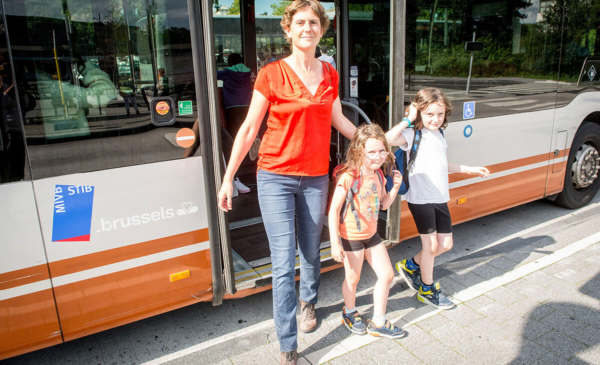 Een vrouw en haar twee kinderen stappen uit een bus